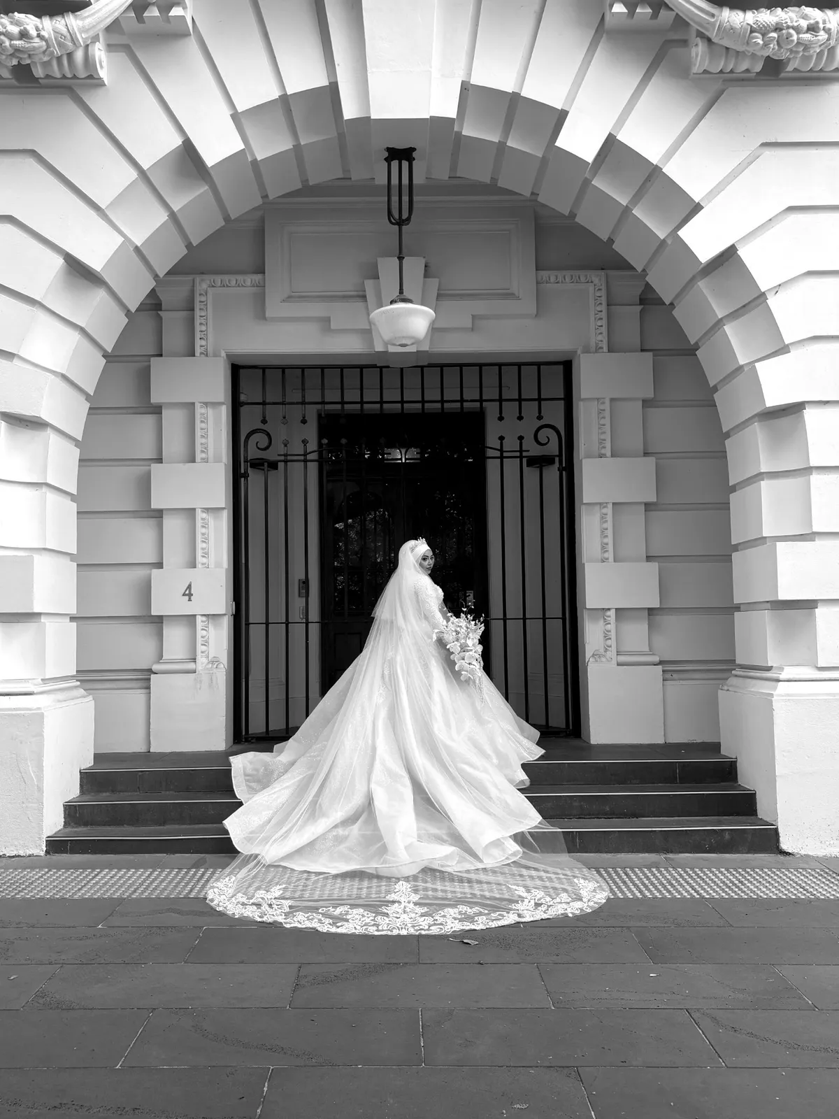 Bride beneath a stone arch, black and white